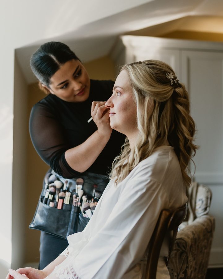 Emily doing a bride's makeup on her wedding morning