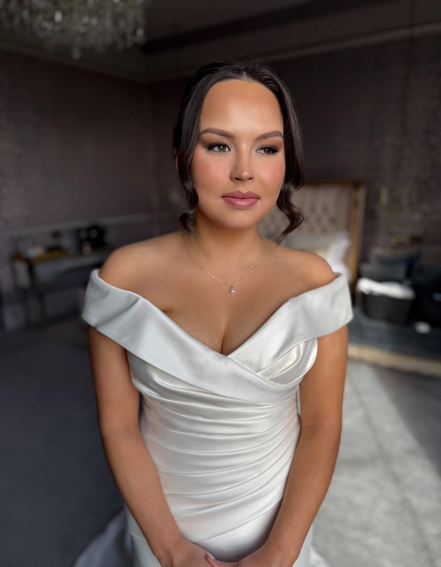 A bride in an off-the-shoulder dress with soft glam makeup, by By.EmWebster